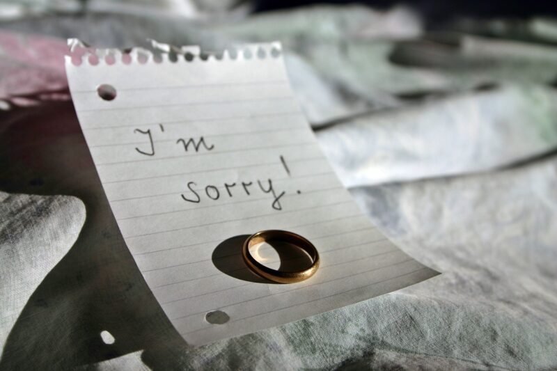 Black and white photo of a wedding ring lying on a sheet of notepaper saying "I'm sorry!"