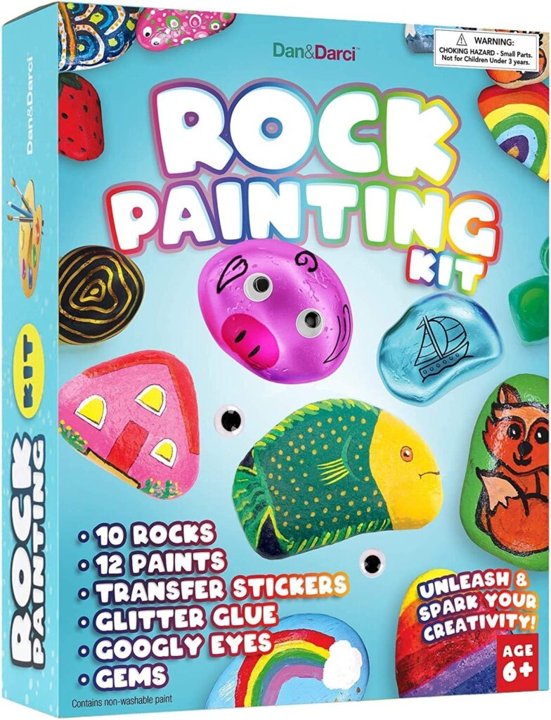 Art gifts for kids include this rock painting kit. the box features rocks painted as different things including a face, house, etc.