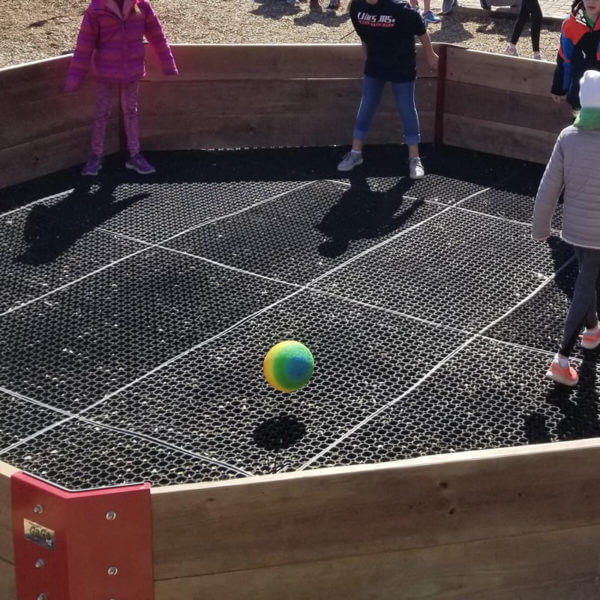 Children's playing gaga ball in a pit with rubber flooring tiles.