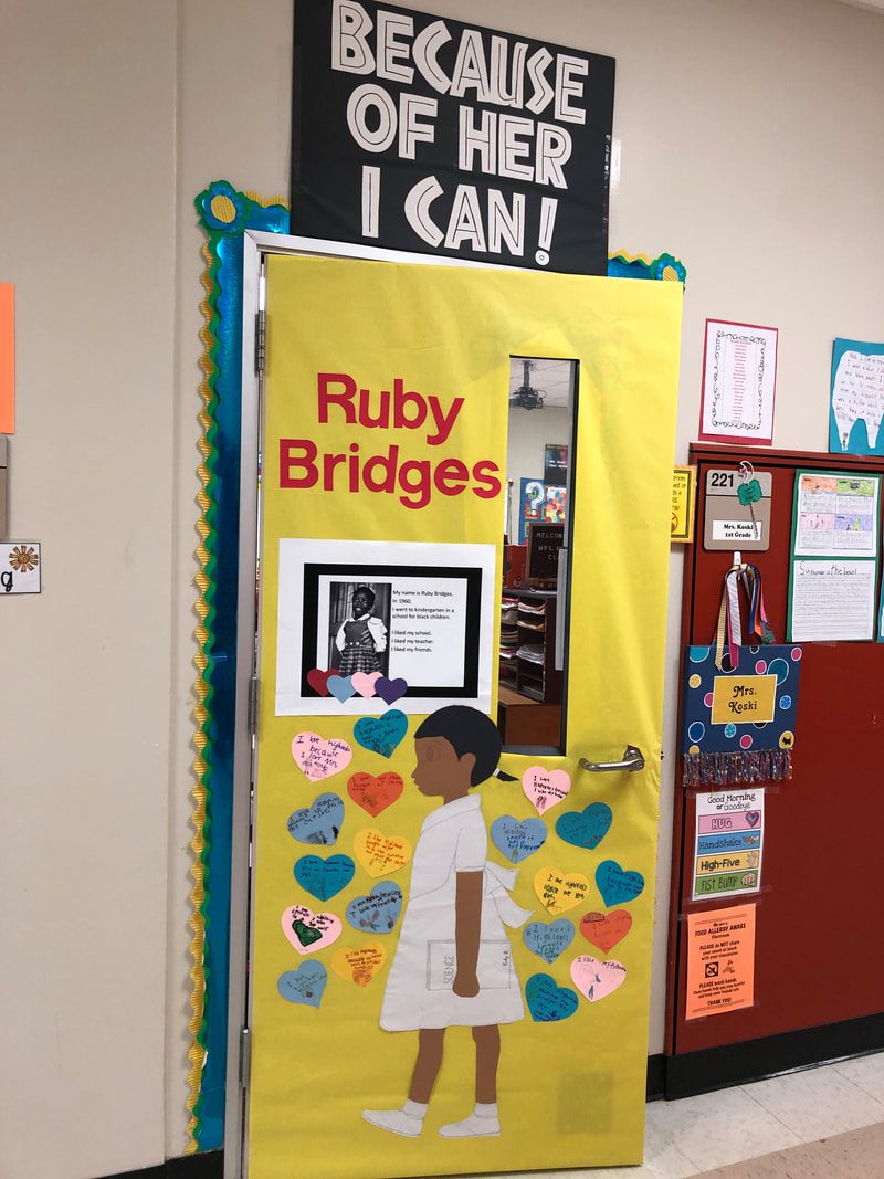A door says Ruby Bridges and includes a photograph of her. Most of the door is covered in hearts and a side cut out of a little girl meant to be Bridges (black history month bulletin board)