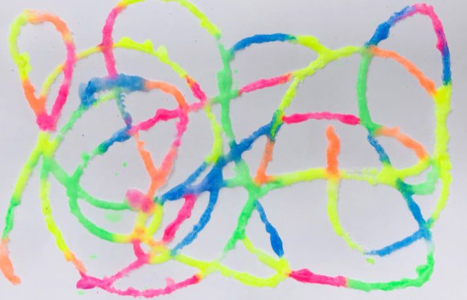 Brightly colored puffy paint is swirled across a paper. 