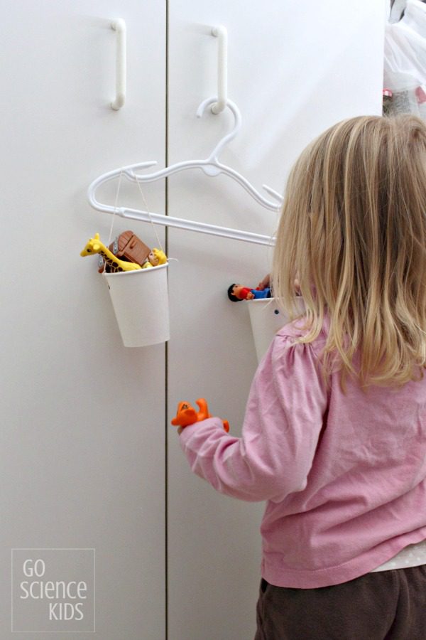 A little girl filling a cup in a homemade scale.