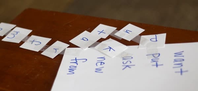 Cards with handwritten letters sitting alongside a sheet with sight words written on it
