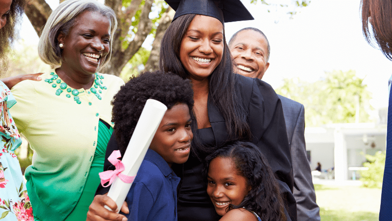 College graduate hugging family members after receiving scholarships for Black students.