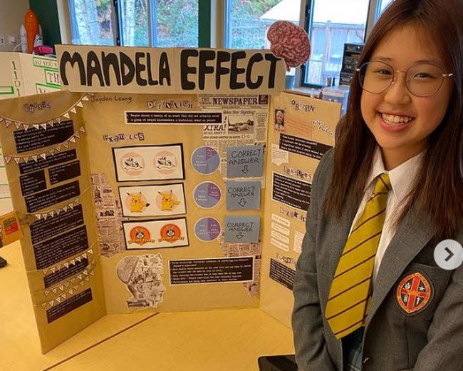 Student standing with her science fair project board on the mandela effect