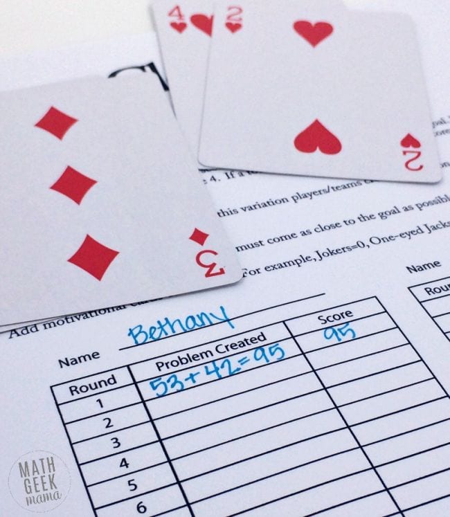 Four playing cards and a printed worksheet with equations and scores