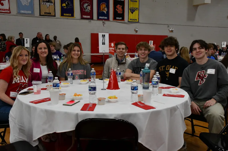 Senior students and their parents sit at a table covered with a white tablecoth