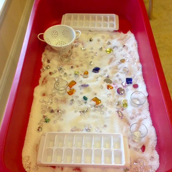 A sensory bin filled with epsom salt, gems and more