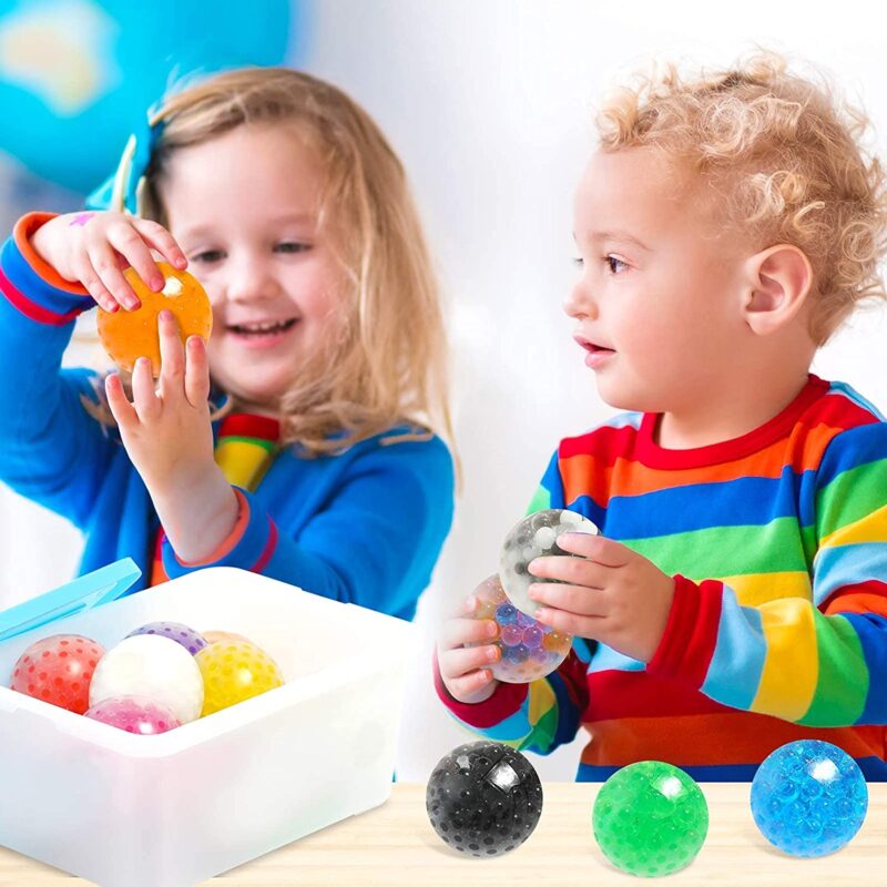 Two small kids are playing with sensory balls that have gel beads inside them and are squishy.
