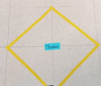 painter's tape creates a rhombus on the floor and tape in the middle labels it.