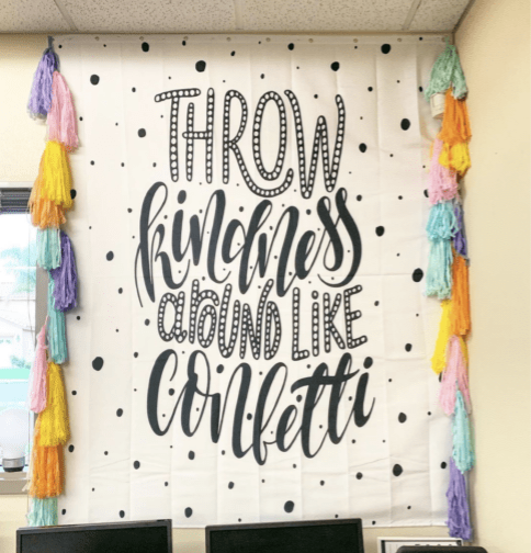 Instagram-worthy teacher hacks include using shower curtains as decor like this one hanging up in a classroom that says throw kindness like confetti.