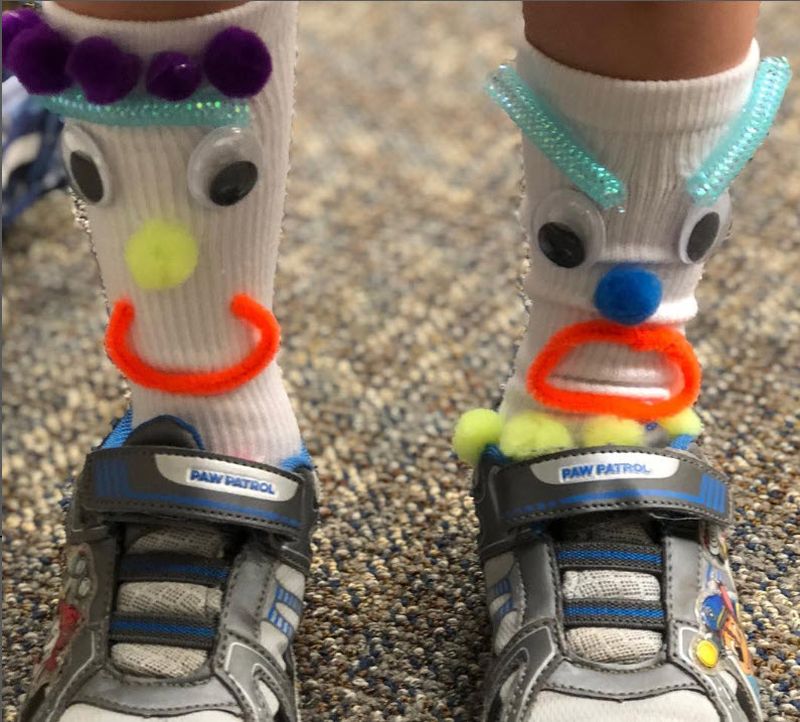 Socks with silly faces made from wiggly eyes, pompoms, pipe cleaners, and more
