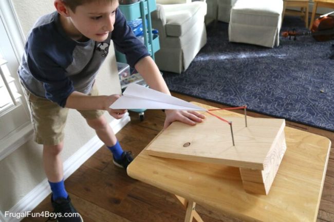 Sixth grade science student using a homemade launcher to launch a paper airplane