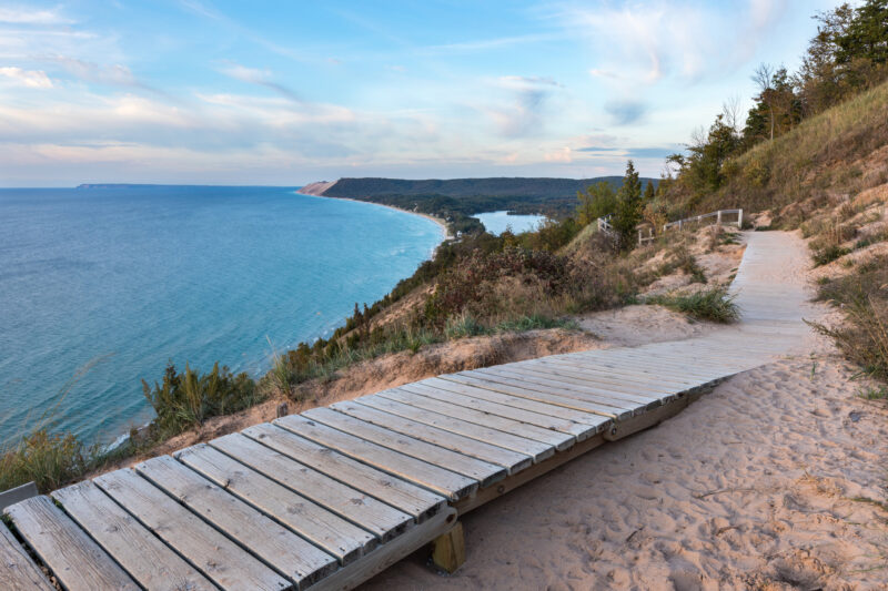A weathered wooden walkway on the Empire Bluffs Trail is the perfect overlook to see Lake Michigan, the Sleeping Bear Dunes, and the Manitou island, as an example of the best family vacations