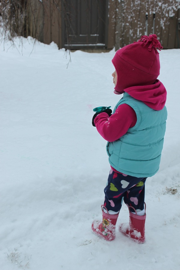 girl using a squirt gun to paint snow for fun winter activities
