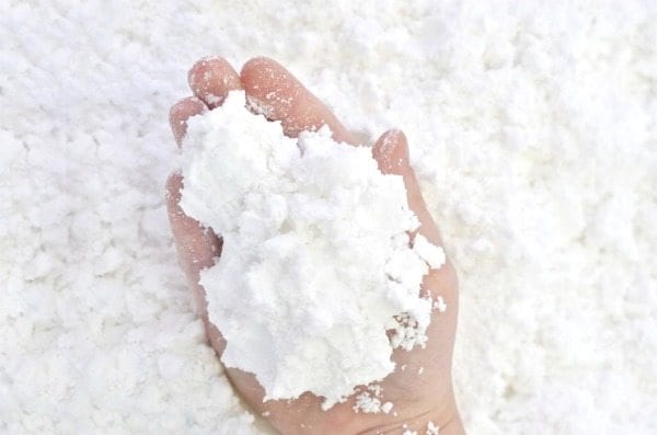 a hand filled with an artificial snowball against a background of artificial snow