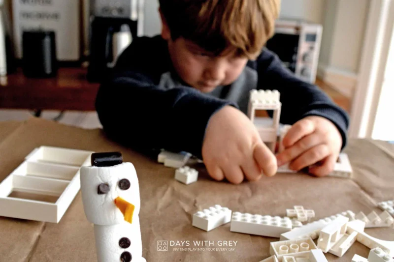 kid building a house for a snowman out of lego bricks for a fun winter activity 