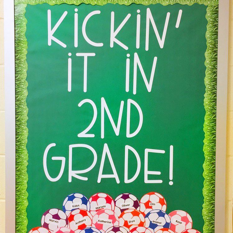 A green background has white lettering that says "Kickin' it in 2nd grade!" There are a pile of different colored soccer balls underneath with names on them.