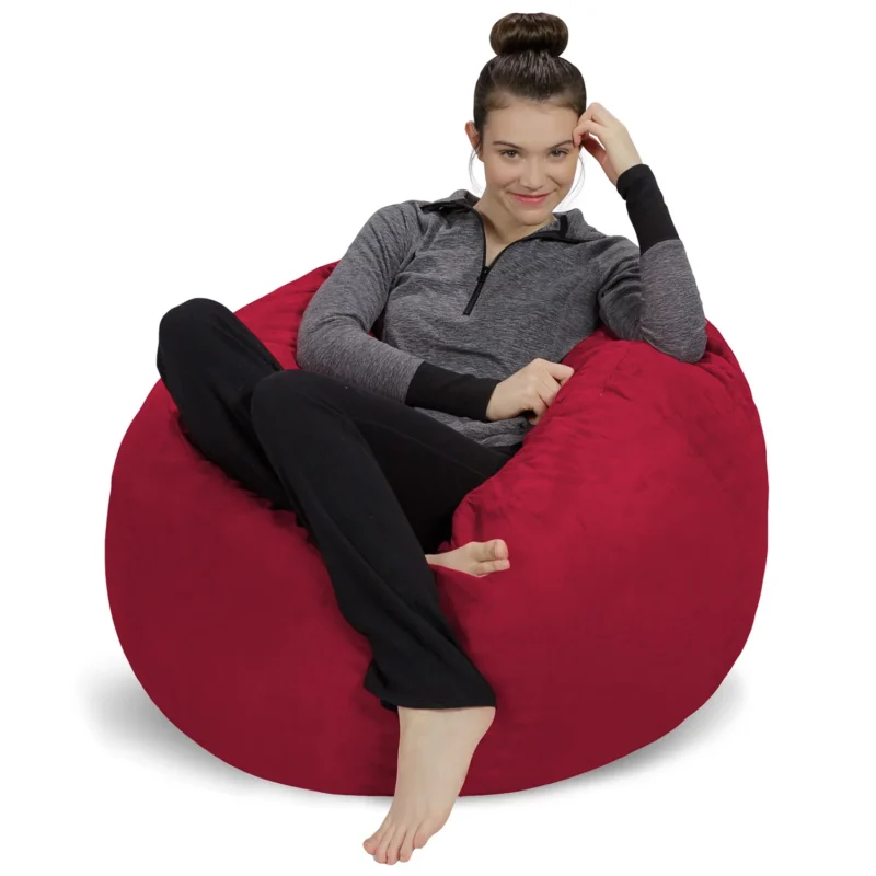 A teenage girl is seen lounging on a burgundy microsuede bean bag chair.