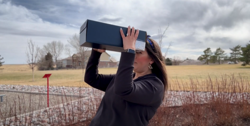 Teacher outside looking through DIY solar eclipse viewer.