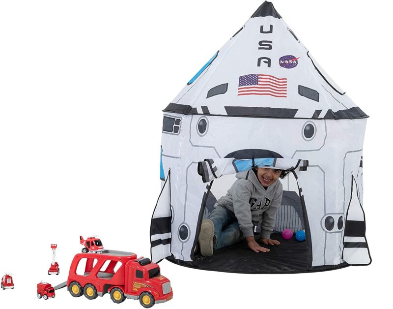 Young boy playing with toy fire truck inside space shuttle pop-up tent