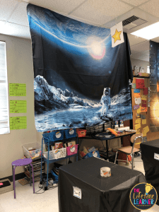 A large curtain with an astronaut on the moon is shown in this space-themed classroom.