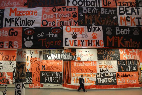 A student walks by a wall covered with black and orange spirit posters