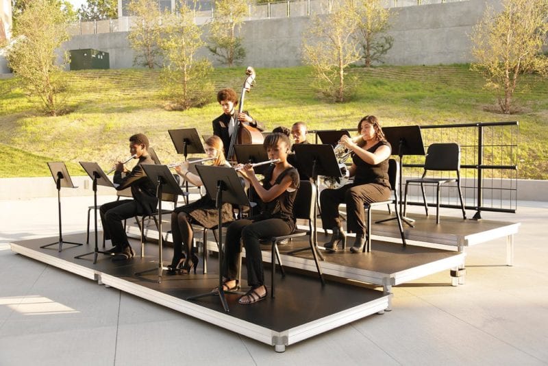 6 students playing instruments outside on risers