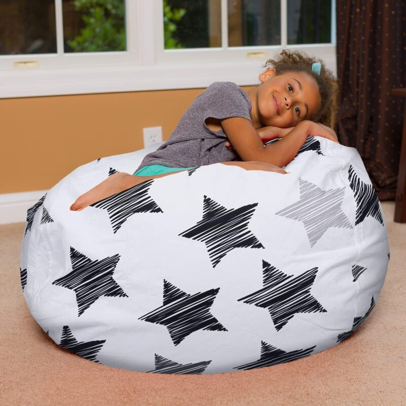 A little girl is shown resting on this example of bean bag chairs for kids. The chair is white with large black stars on it.