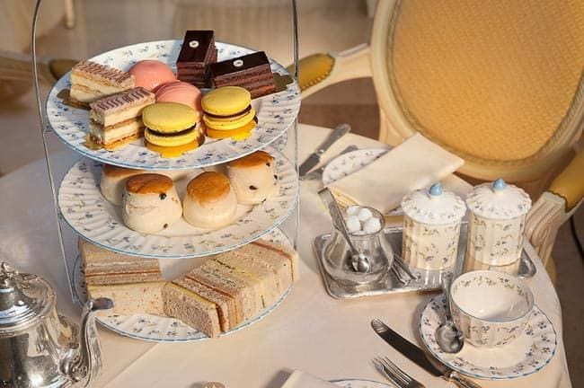 Teapot, teacups, and cake stand with treats on a table (Staycation Activities)