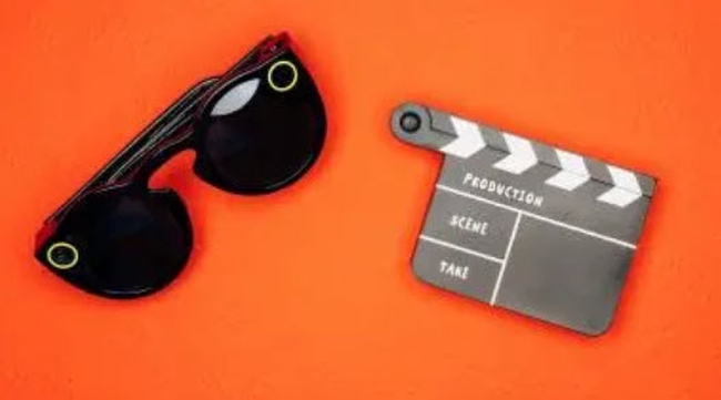 Sunglasses and film clapboard on an orange background