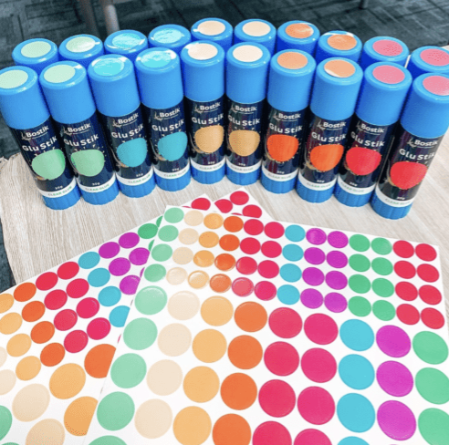 Instagram-worthy teacher hacks include putting different colored dot stickers on a bunch of glue sticks and their lids as shown here.