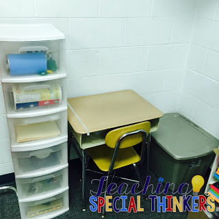 A set of white plastic drawers with clear fronts are shown beside a student desk.