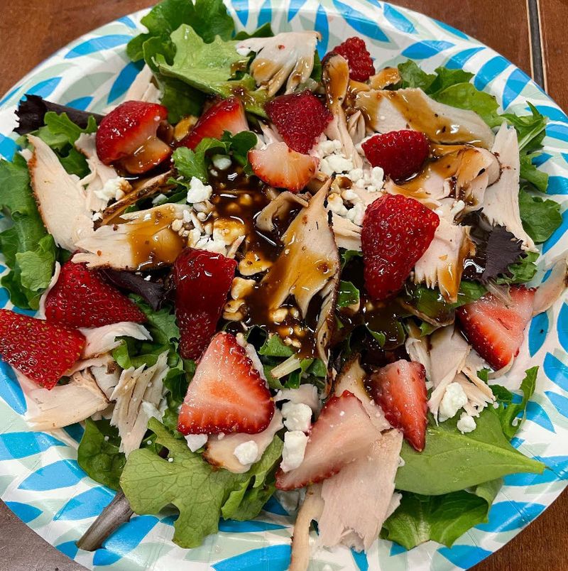 Blue and white bowl holding salad made of lettuce, turkey, strawberries, and more