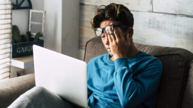 Asian man rubbing eyes in front of laptop pandemic neurological changes