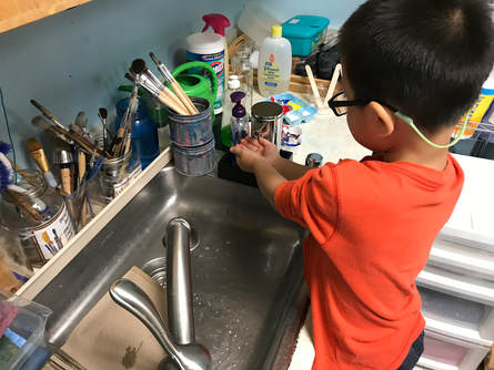 Boy in orange shirt in front of a classroom sink