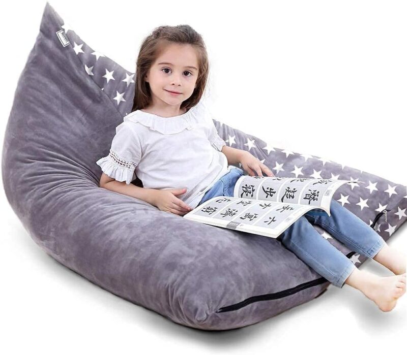 A gray triangular shaped bean bag chair with a zipper is shown with a little girl on it.