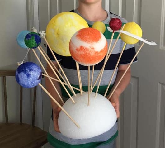 Styrofoam balls are painted to look like the sun and planets and are attached to a larger styrofoam base with skewers. 