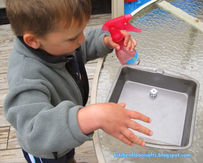 child holding spray bottle and looking at dice 