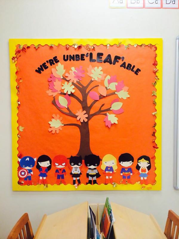 Board reads "we're unbe "leaf" able. A fall tree is pictured with several recognizable superheros beneath including captain america, supergirl, and batman.