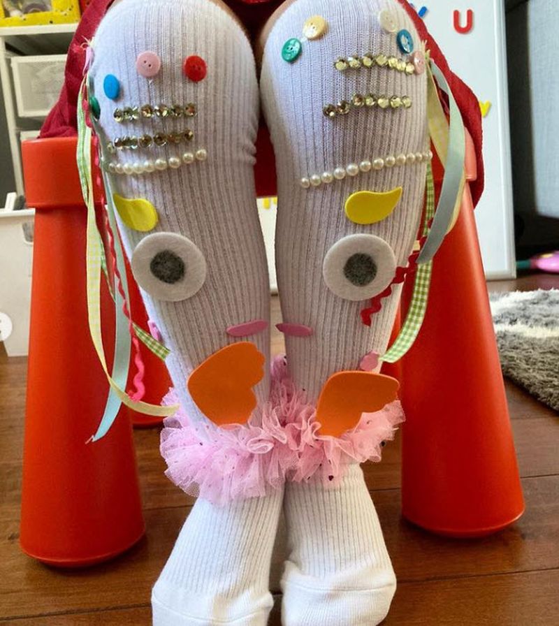 Knee high white socks with eyes and a mouth, decorated with jewels, ribbons, and tulle
