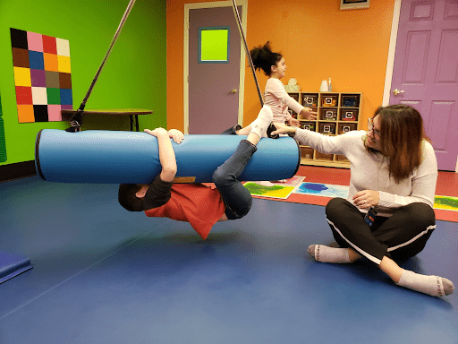Kid playing on swinging log in classroom, as an example of sensory room ideas