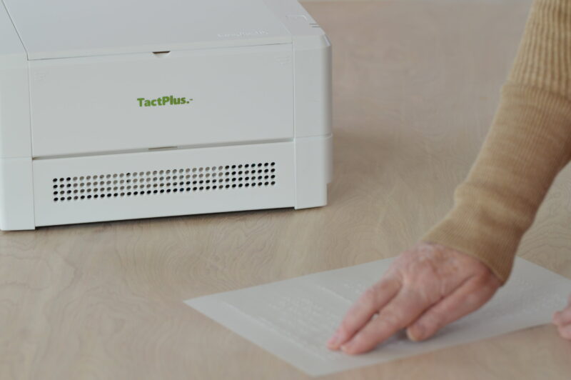 someone reading a braile page after printing it off a braille printer - assistive technology examples
