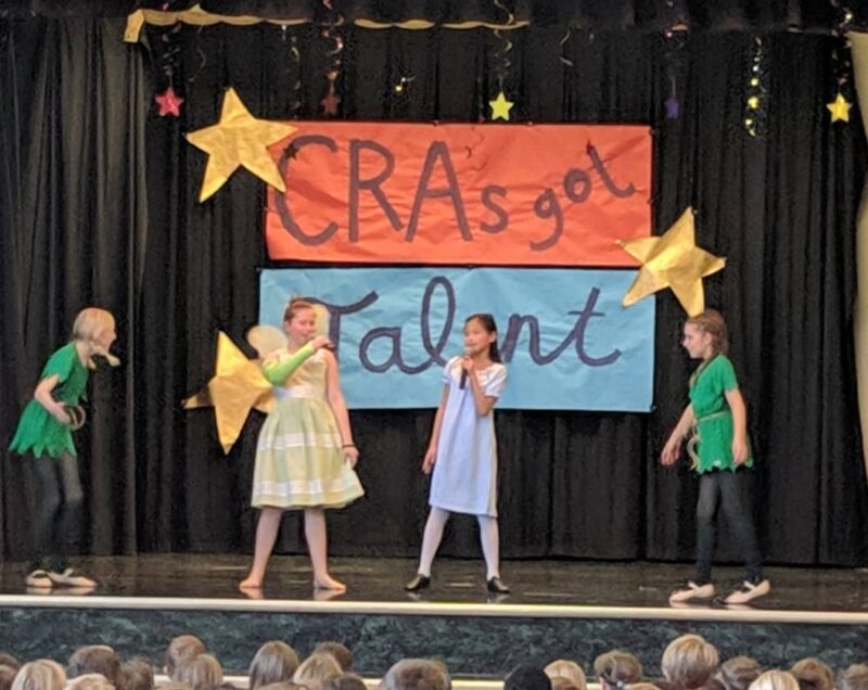 Students performing on a stage with a sign saying CRA's Got Talent