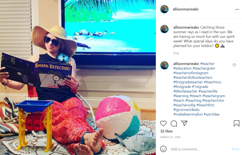 Teacher sitting in a chair surrounded by the accoutrements of a beach visit reading the book Shark Detective while in front of a TV screen featuring a beach scene