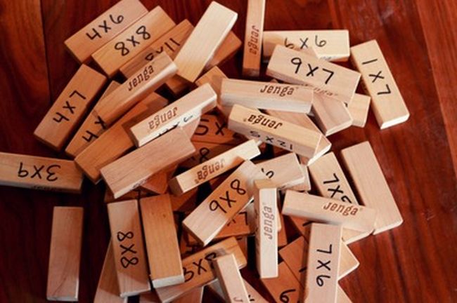 A jumble of Jenga wooden blocks with multiplication facts written on them used to teach multiplication