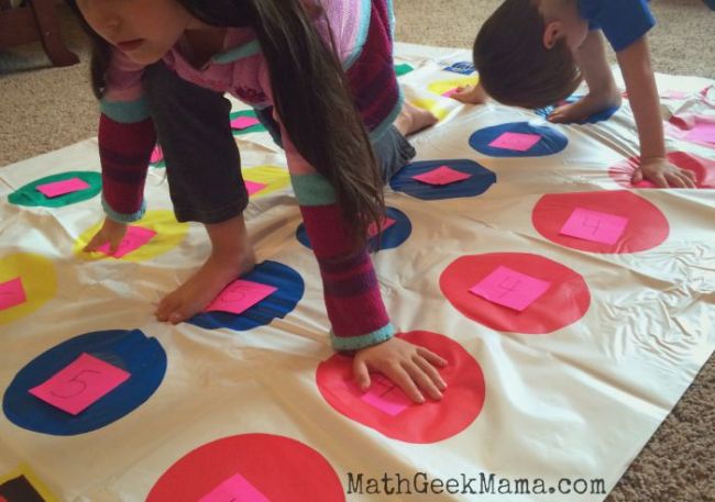 Kids playing Twister on a Twister mat with numbers written on each dot