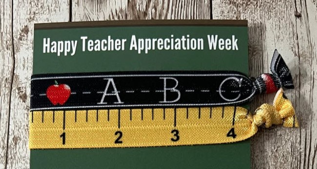 Two elastic hair ties, one with a chalkboard theme and one with a ruler theme, on a card that reads "Happy Teacher Appreciation Week"