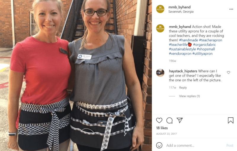 Teachers wearing black and white aprons pose outside of school together