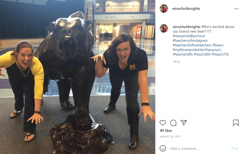 Two teachers on either side of a bear mascot statue in middle school